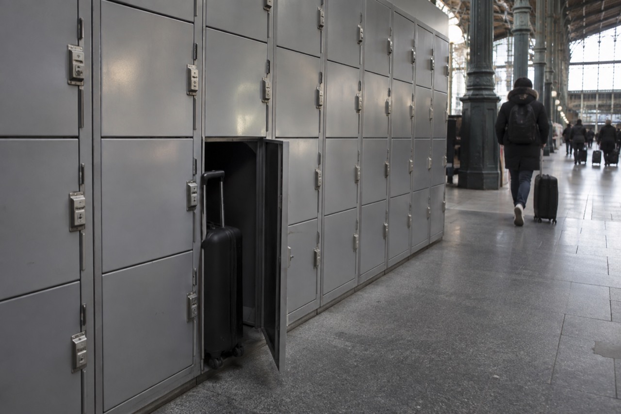 A row of grey self-service lockers in a Paris railway station corridor