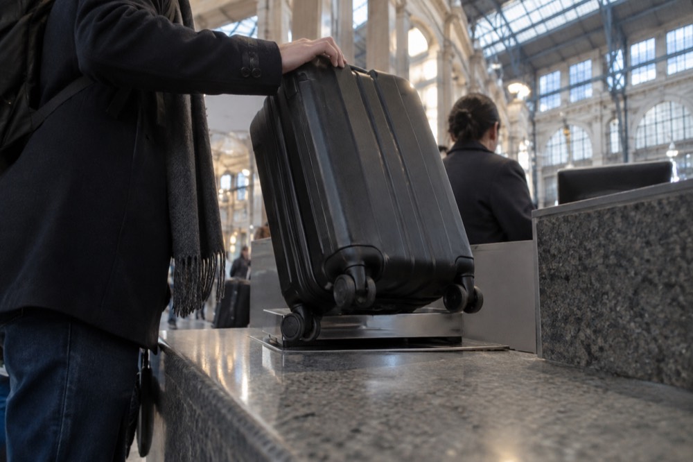 A left luggage counter in an airport terminal with a suitcase being handed over