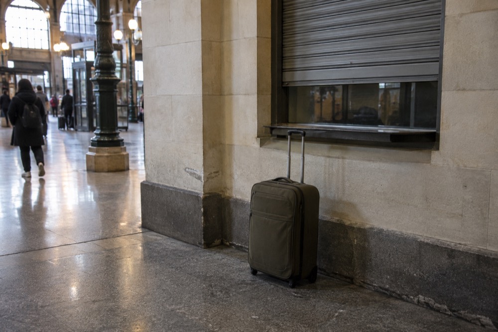 A closed counter window in a Paris station corridor with a suitcase waiting in front of it