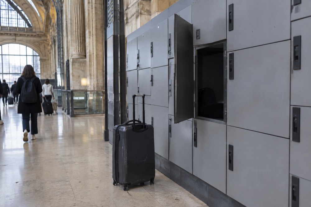 Rows of grey self-service luggage lockers along a station corridor wall