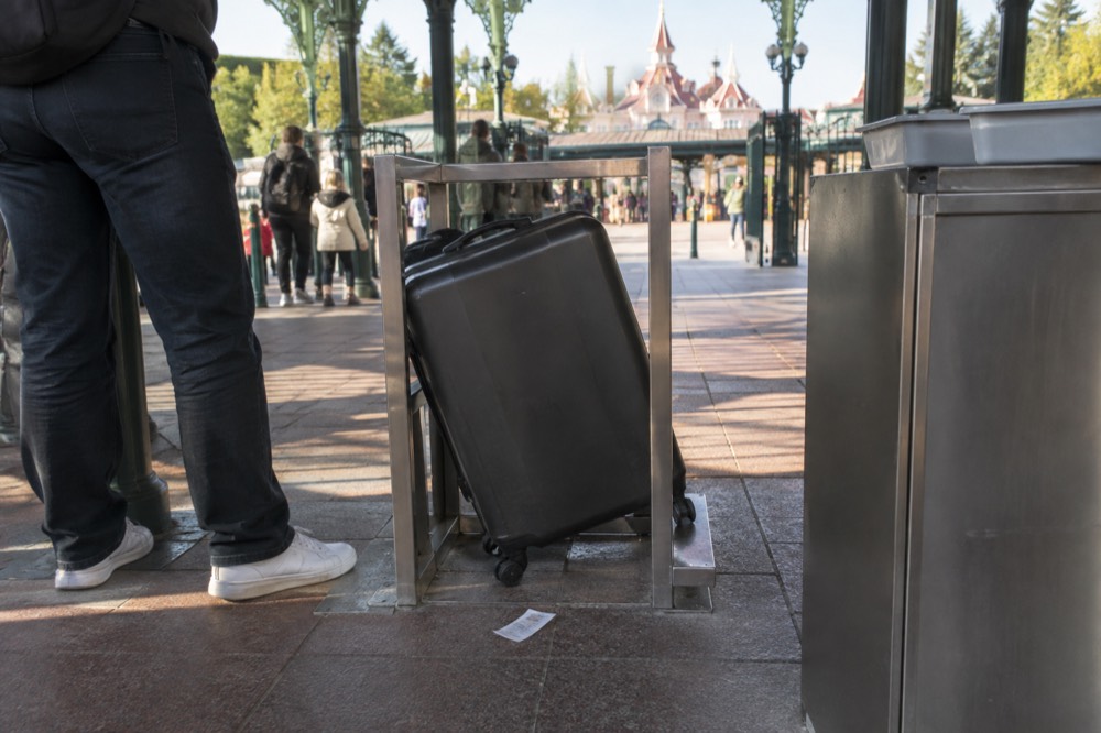 A security checkpoint entrance with a bag gauge beside the gate at a theme park