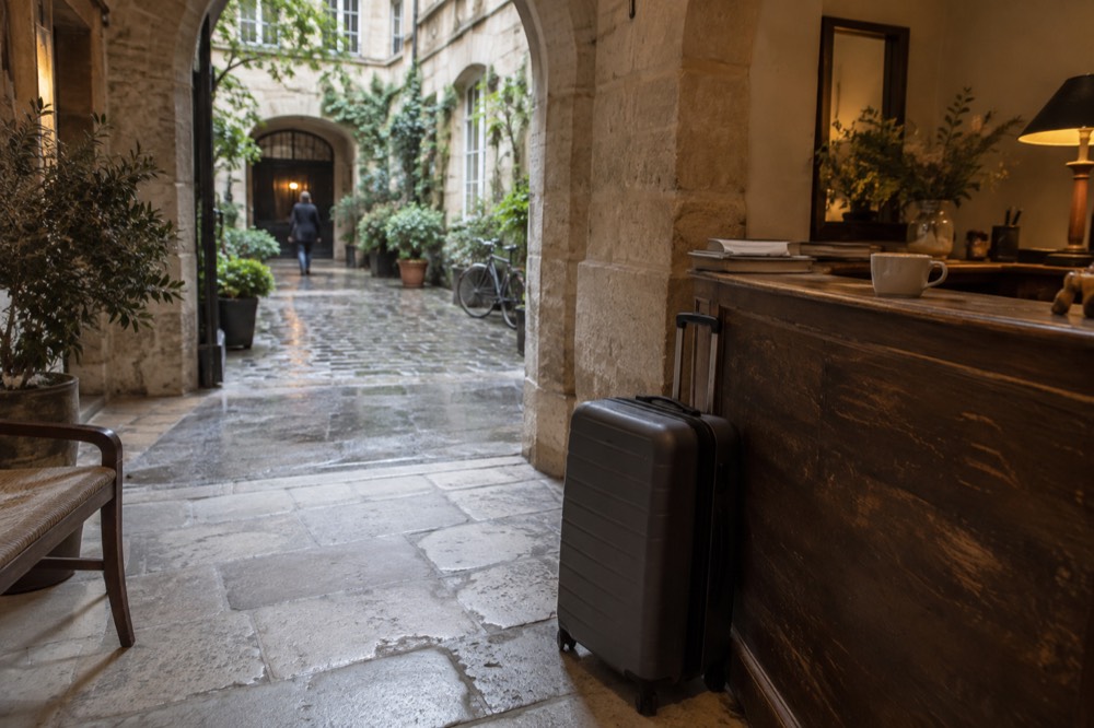 Suitcase waiting beside a hotel reception desk in a Paris lobby