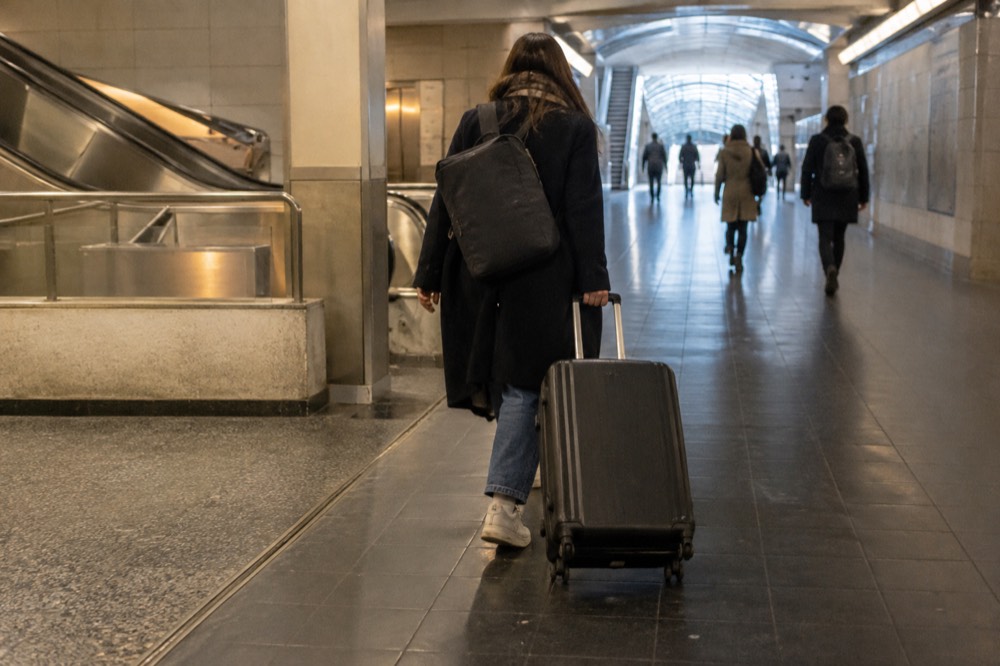 A traveller pulling a wheeled suitcase through a Metro corridor in Paris