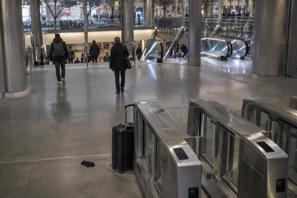 A wide Metro corridor with turnstiles and a suitcase waiting at a gate