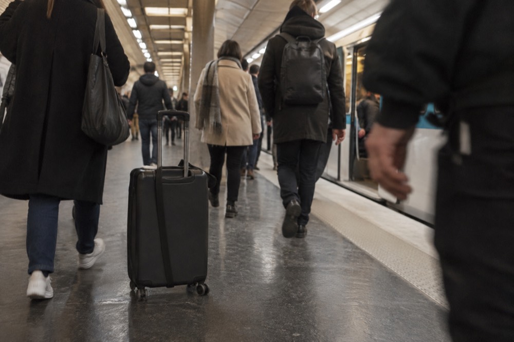 A crowded Metro platform in Paris with a suitcase standing among commuters