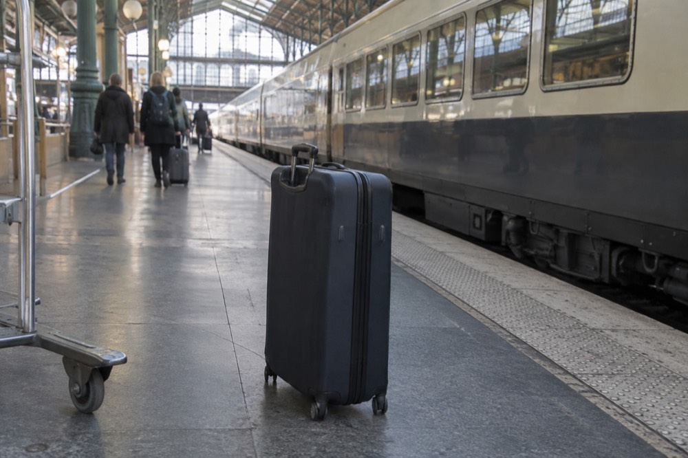 Yellow Eurostar train at the platform in Gare du Nord station beside a closed suitcase