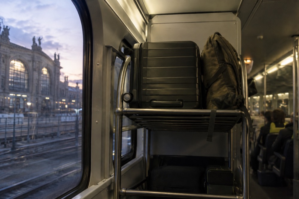 Luggage racks at the end of a high-speed train carriage with a large suitcase and a backpack stowed