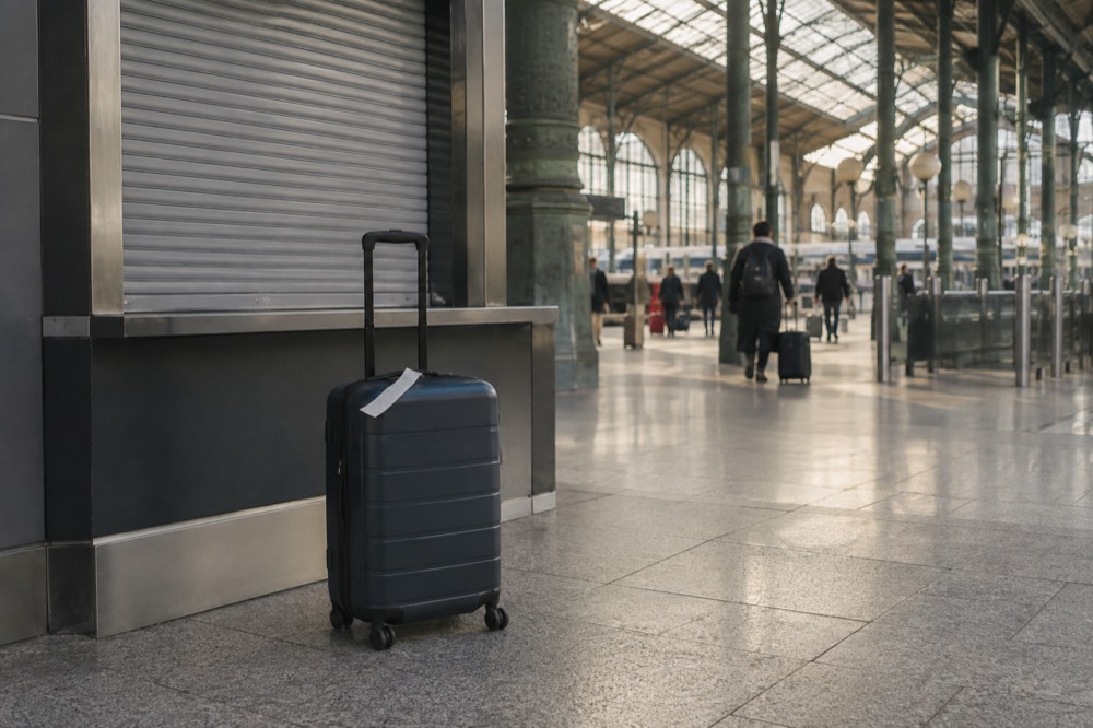 A closed luggage office counter in a Paris train station with a suitcase in front of it
