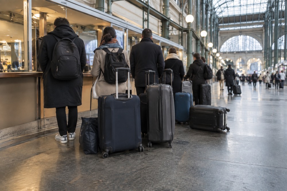 Travellers queuing with suitcases at a left-luggage counter on the lower concourse of Gare du Nord