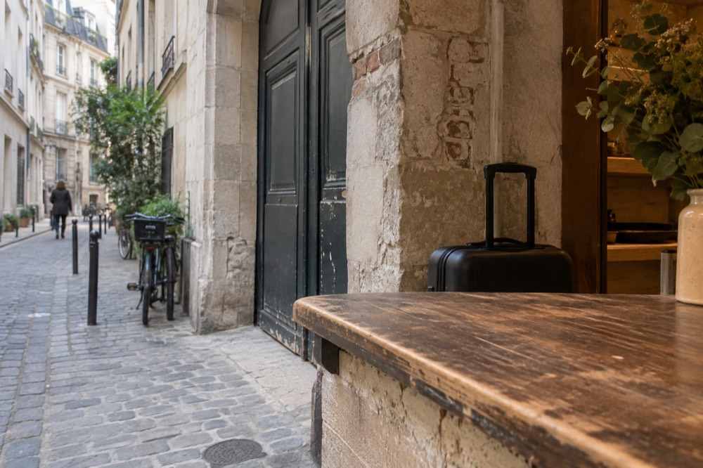 A small shop counter in Paris with a suitcase parked behind it