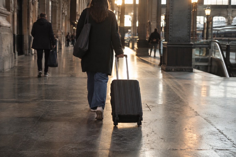 An airport arrivals hall corridor with a trolley suitcase rolling along a polished floor