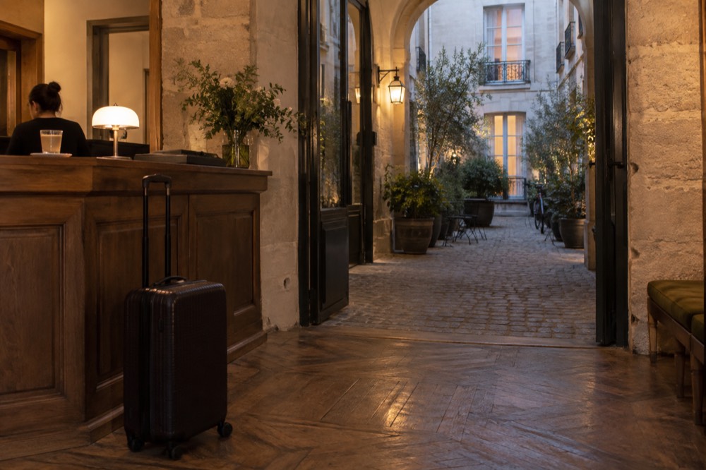 A suitcase waiting beside a hotel reception desk in a Paris lobby