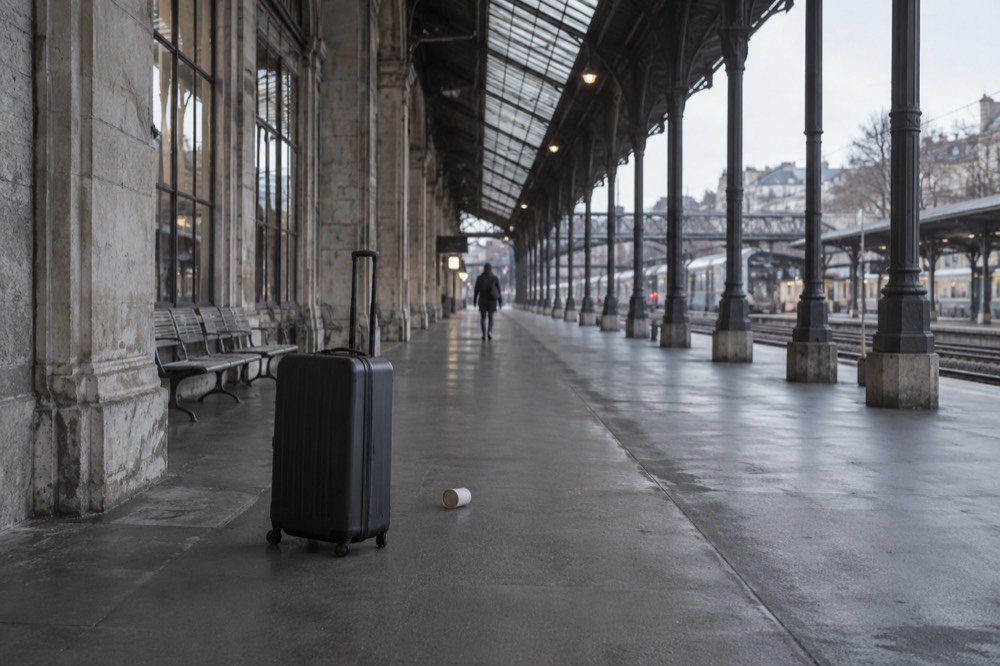 A lone suitcase left standing on an empty Paris station platform