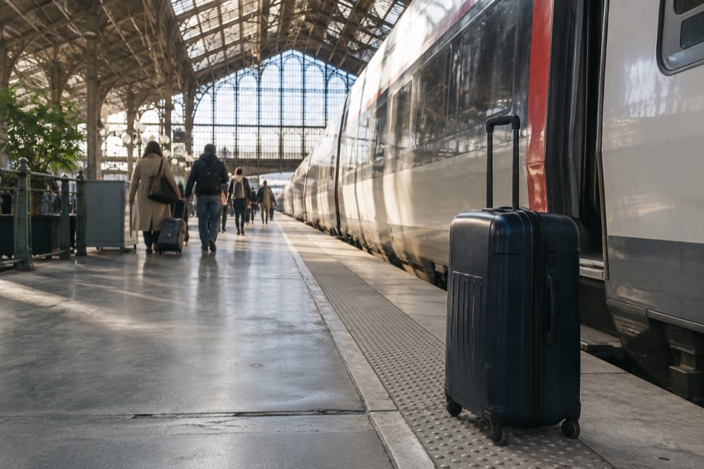 A suitcase standing beside a high-speed train waiting at a Paris platform