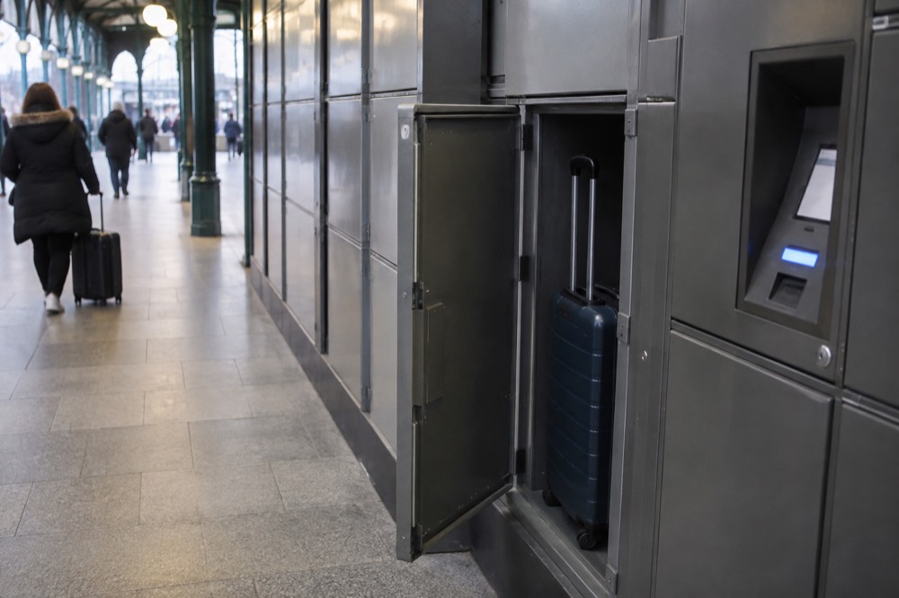Bank of self-service lockers along a station corridor with a card payment terminal