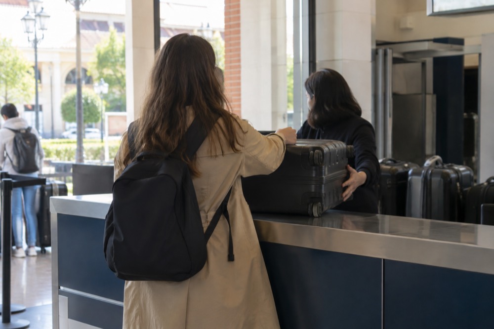 Shop counter where a traveller hands over a suitcase to staff