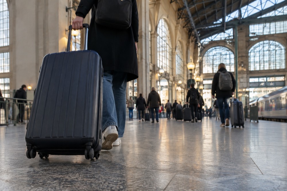 A traveller pulling a large suitcase across the main concourse of Gare du Nord