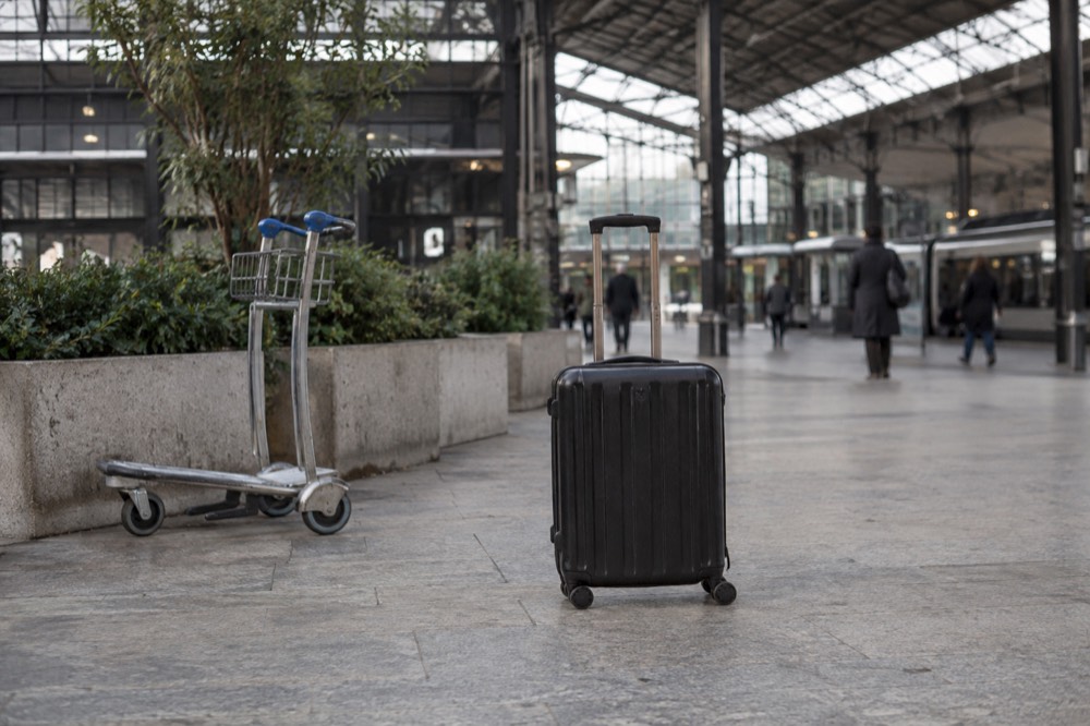 A suitcase waiting in the middle of a wide Paris station concourse