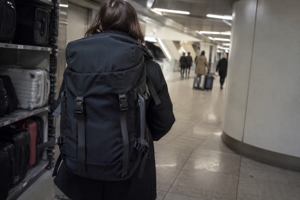 A traveller walking with a backpack through a Paris arcade leaving a stored suitcase behind