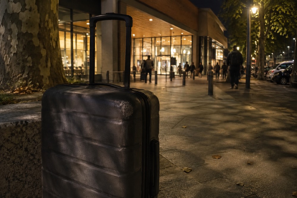 A suitcase outside an illuminated Paris shopfront at night