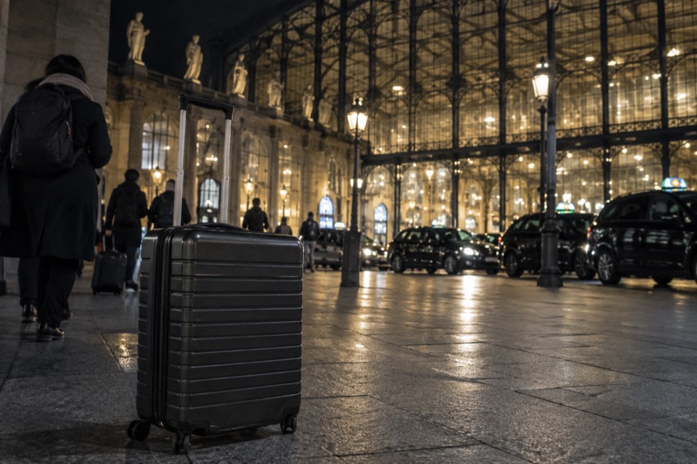 Suitcases on the pavement outside Gare du Nord at night with taxi lights behind