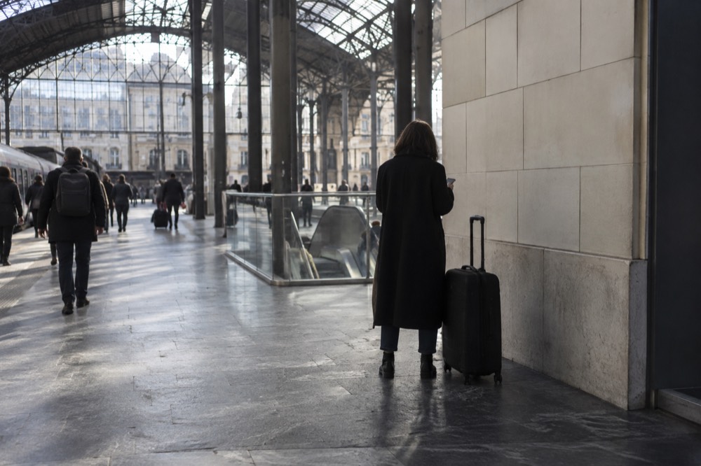 A suitcase standing on a station concourse next to a tiled wall