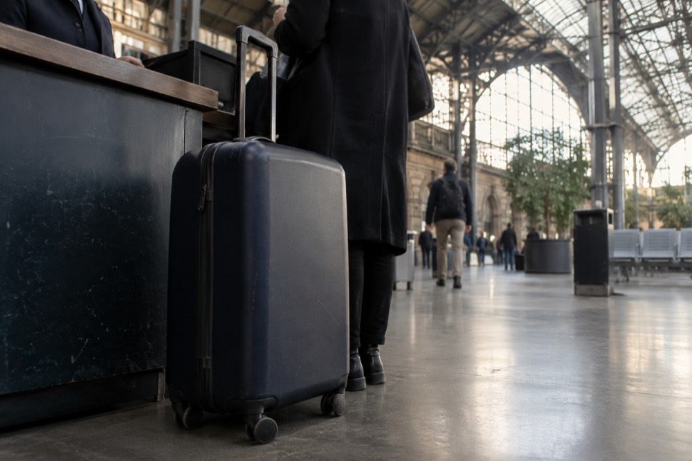 A suitcase set on the floor at a staffed service counter in an airport terminal near Paris