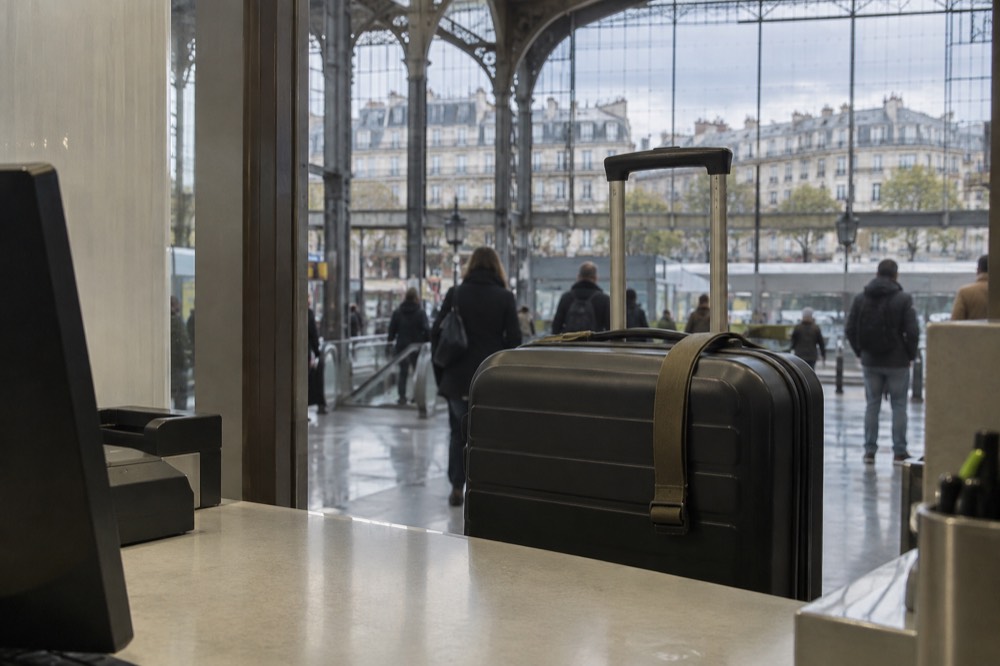 A wheeled case standing at a service counter in an airport arrivals hall near Paris