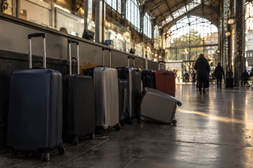 Row of wheeled suitcases parked beside a counter in an airport service area