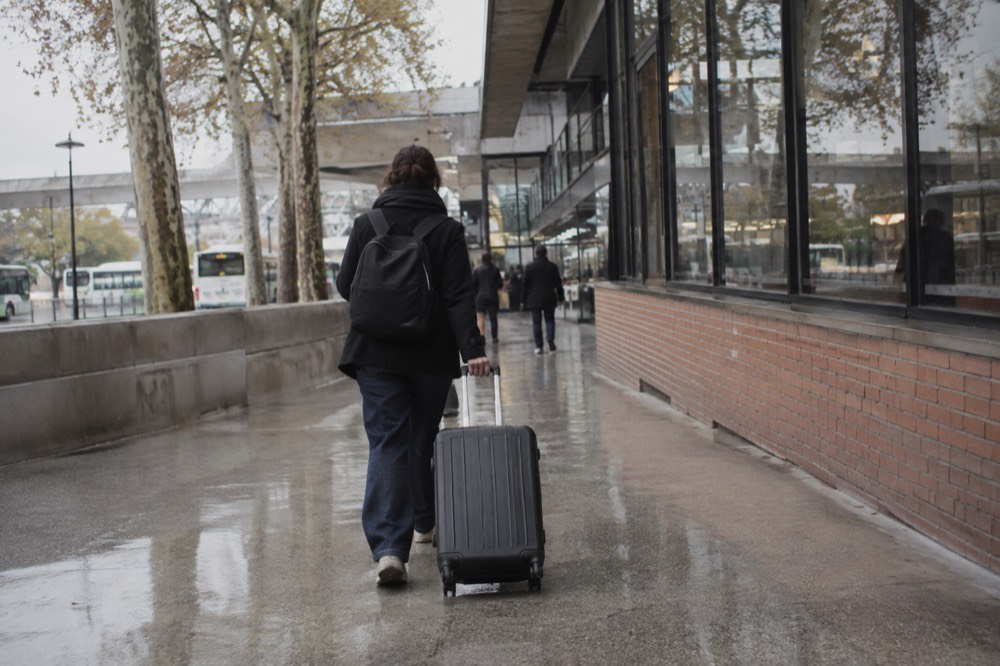 A traveller pulling a suitcase along an airport corridor near Paris
