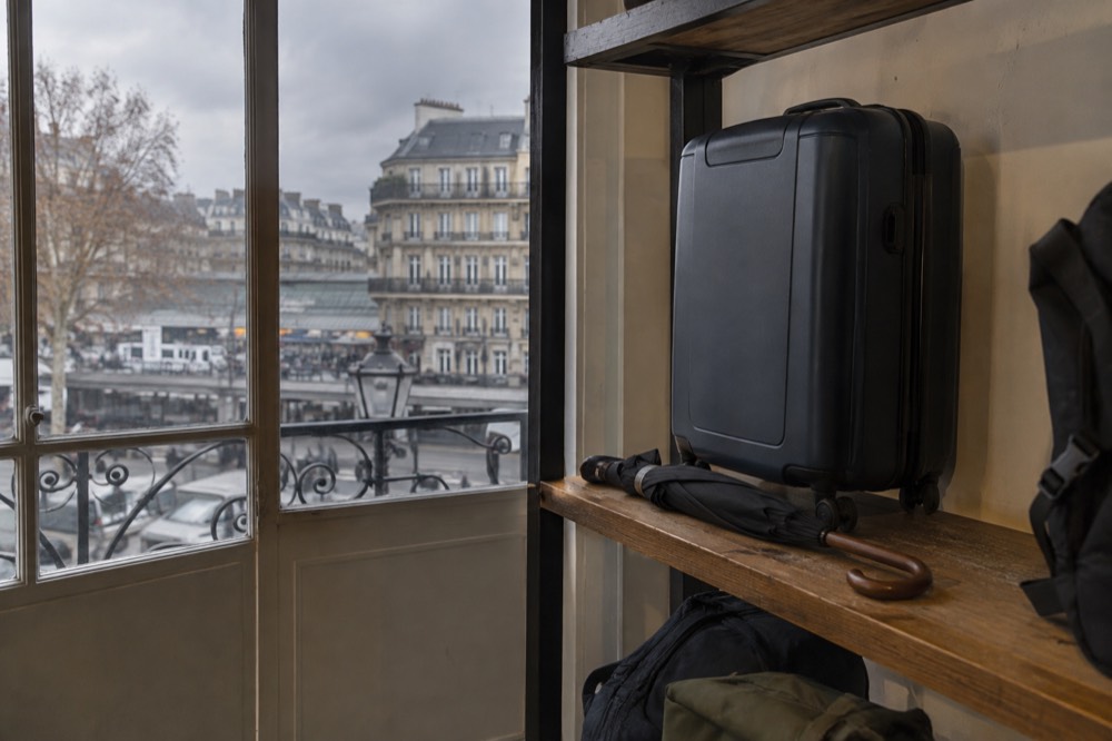 A Paris storage room lined with shelves, one holding a suitcase beside a folded umbrella