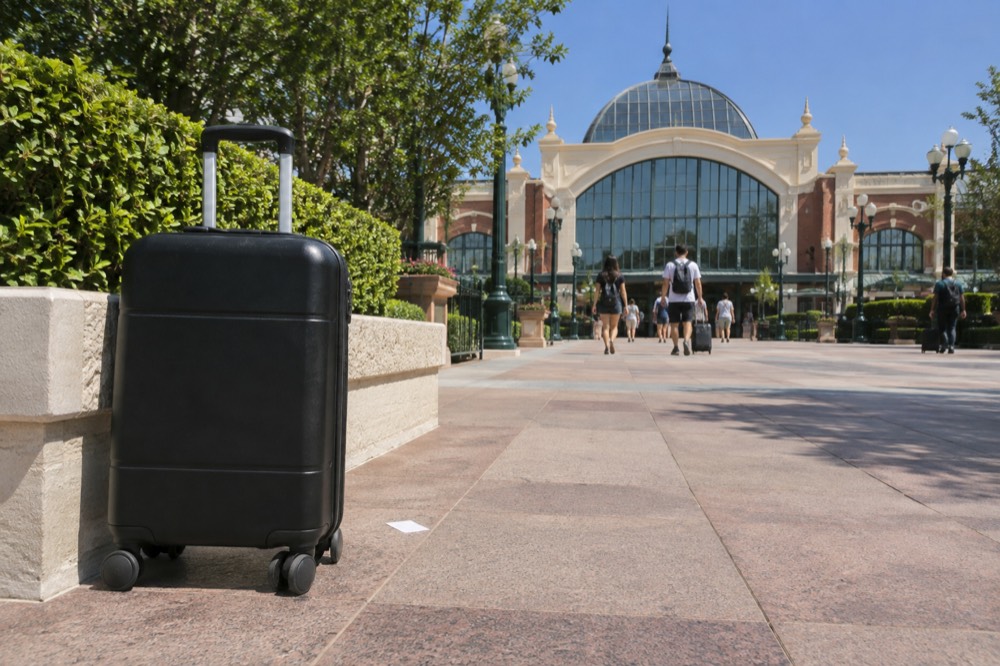 The facade of a Paris mainline railway station seen from a plaza with a suitcase in the foreground