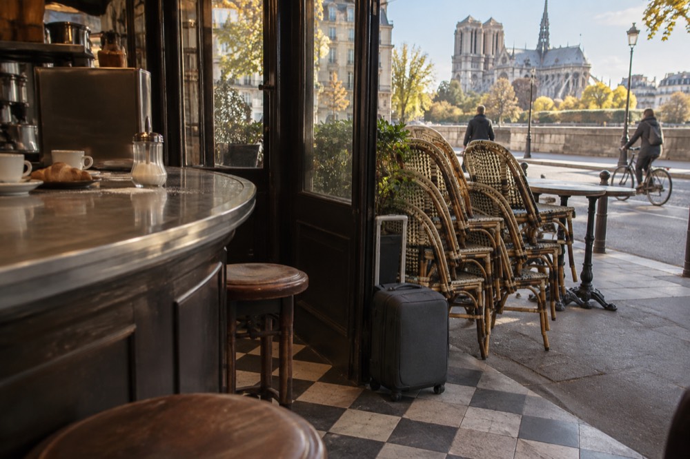 A café counter with a card reader and a small suitcase beside it on the floor