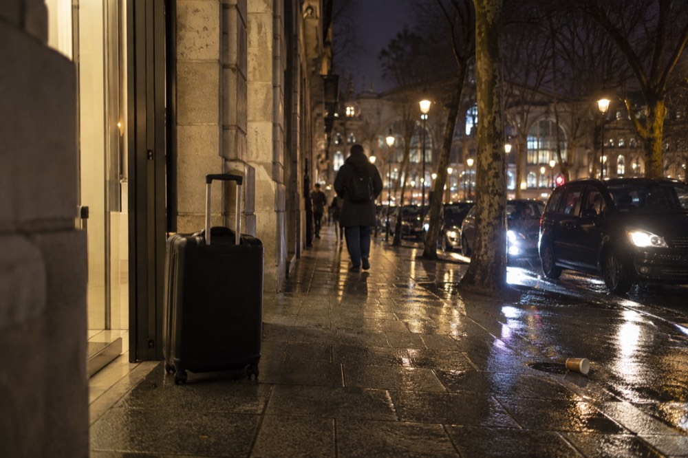 A suitcase outside a lit shop entrance in Paris at night