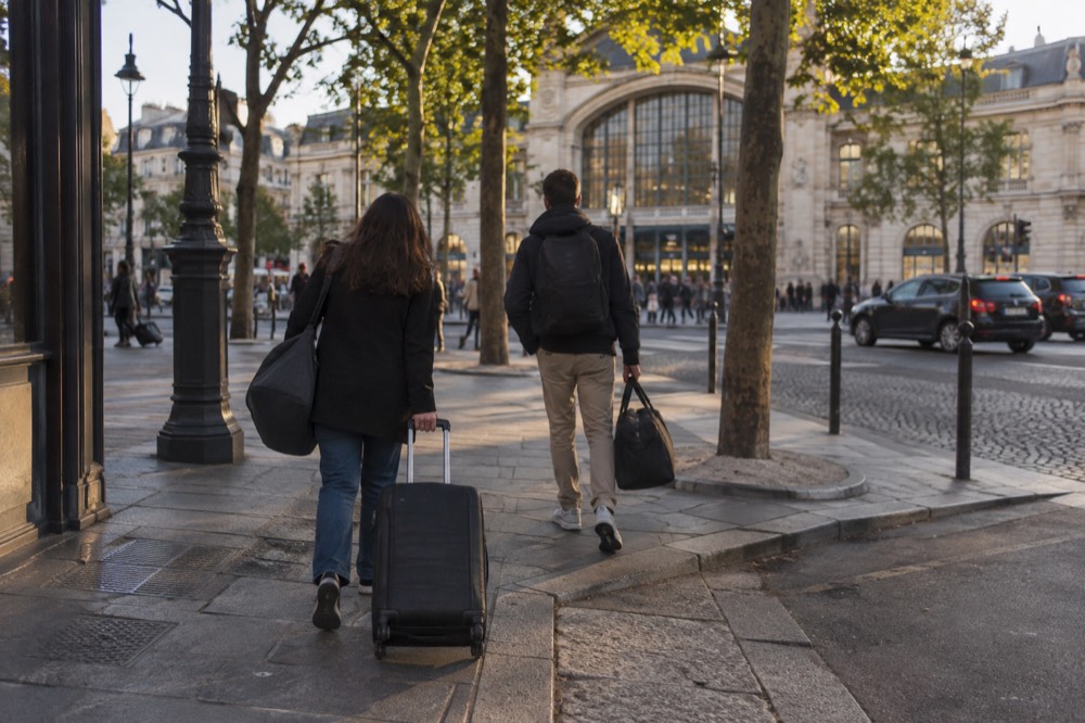 Travellers entering a Paris hotel with luggage after a day of sightseeing