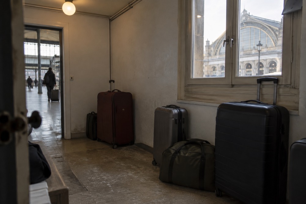 A small hotel luggage room in Paris with a few suitcases parked along the wall