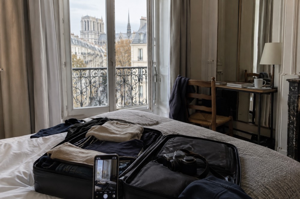 A traveller photographing the contents of an open suitcase on a hotel bed