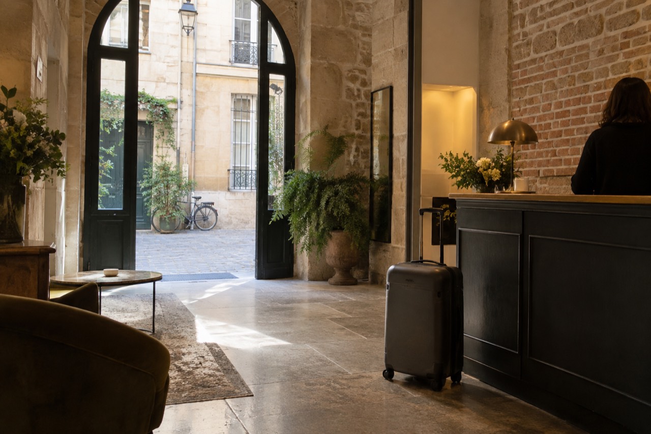 A quiet Paris hotel reception desk with a suitcase parked beside the counter