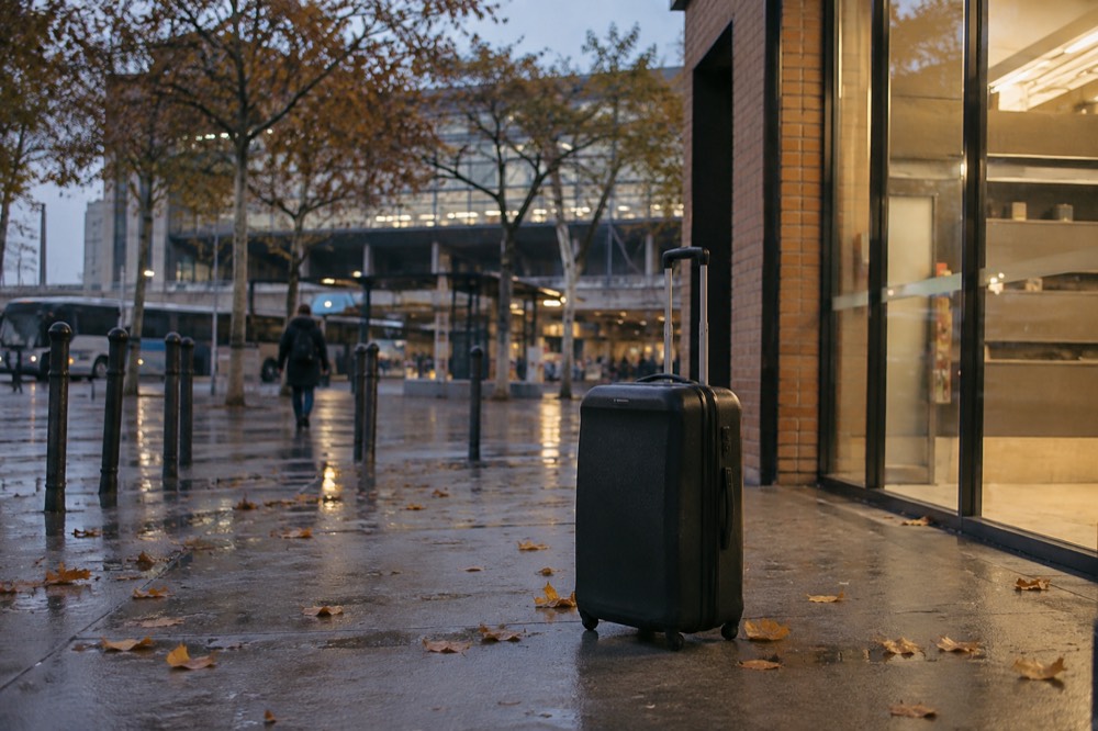 A suitcase on the pavement outside a small shop front near a Paris station