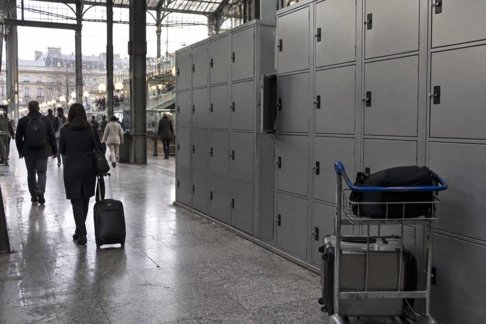 Bank of grey self-service lockers along a station corridor wall