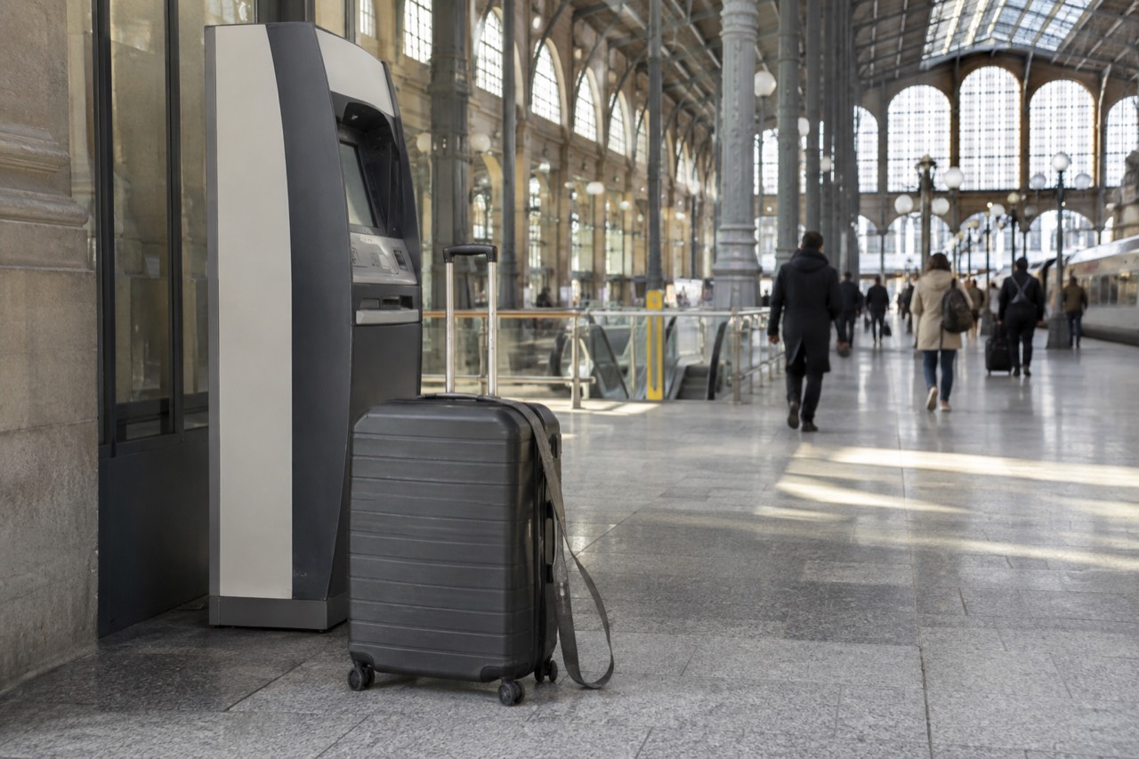 A suitcase standing beside a ticket machine in a Paris train station concourse.