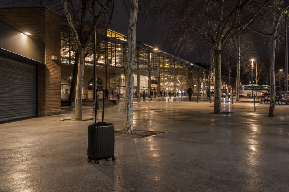 A suitcase on a Paris street at night outside a shuttered shop front