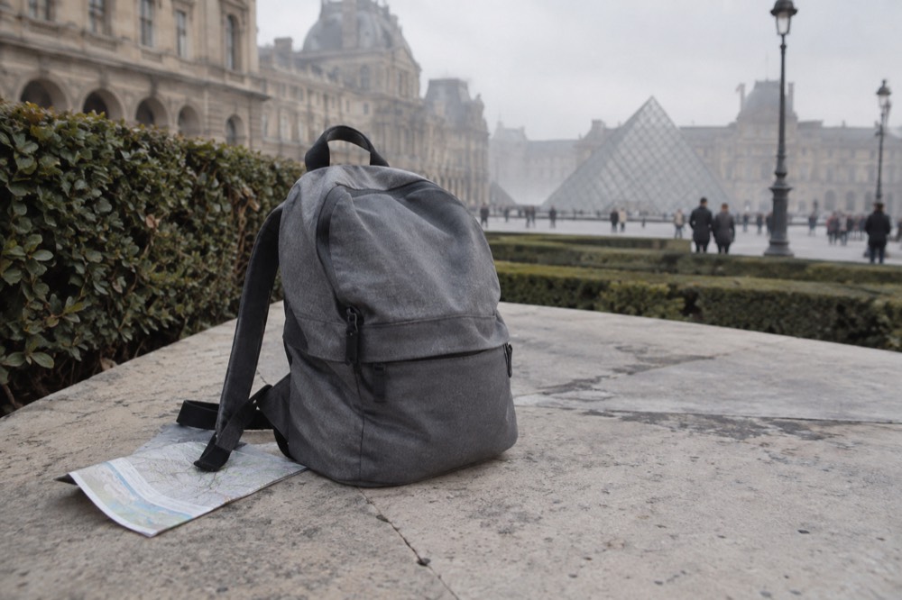 A small rucksack set down on the courtyard plaza by the glass pyramid of the Louvre